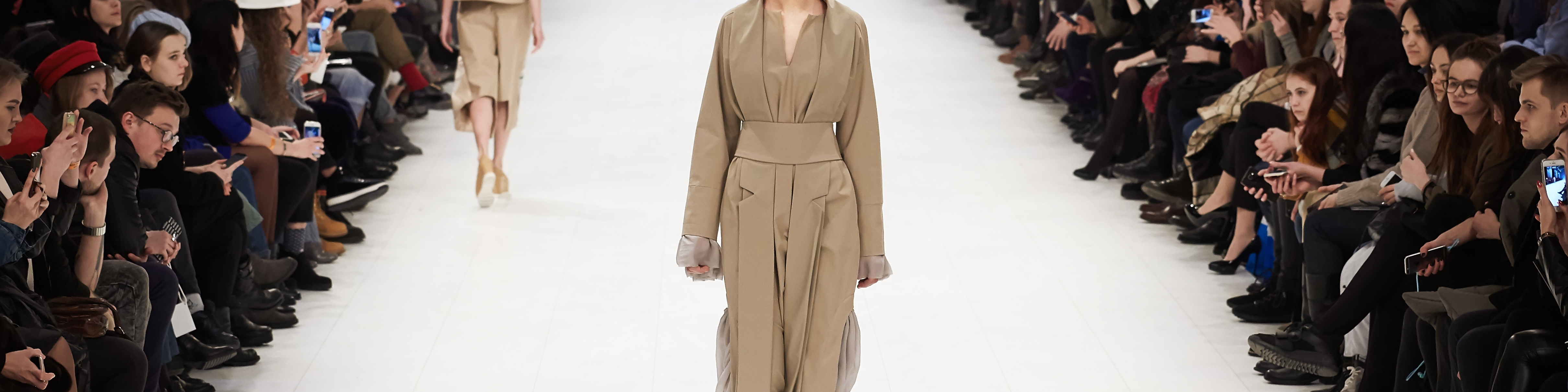 Shutterstock Webum En catwalk med en person i mitten med en trenchcoat och åskådare på varje sida