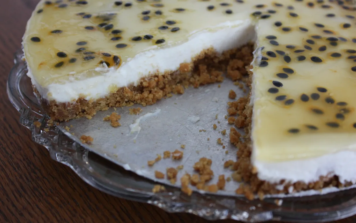 Citroncheesecake med passionsfrukt på ett tårtfat.