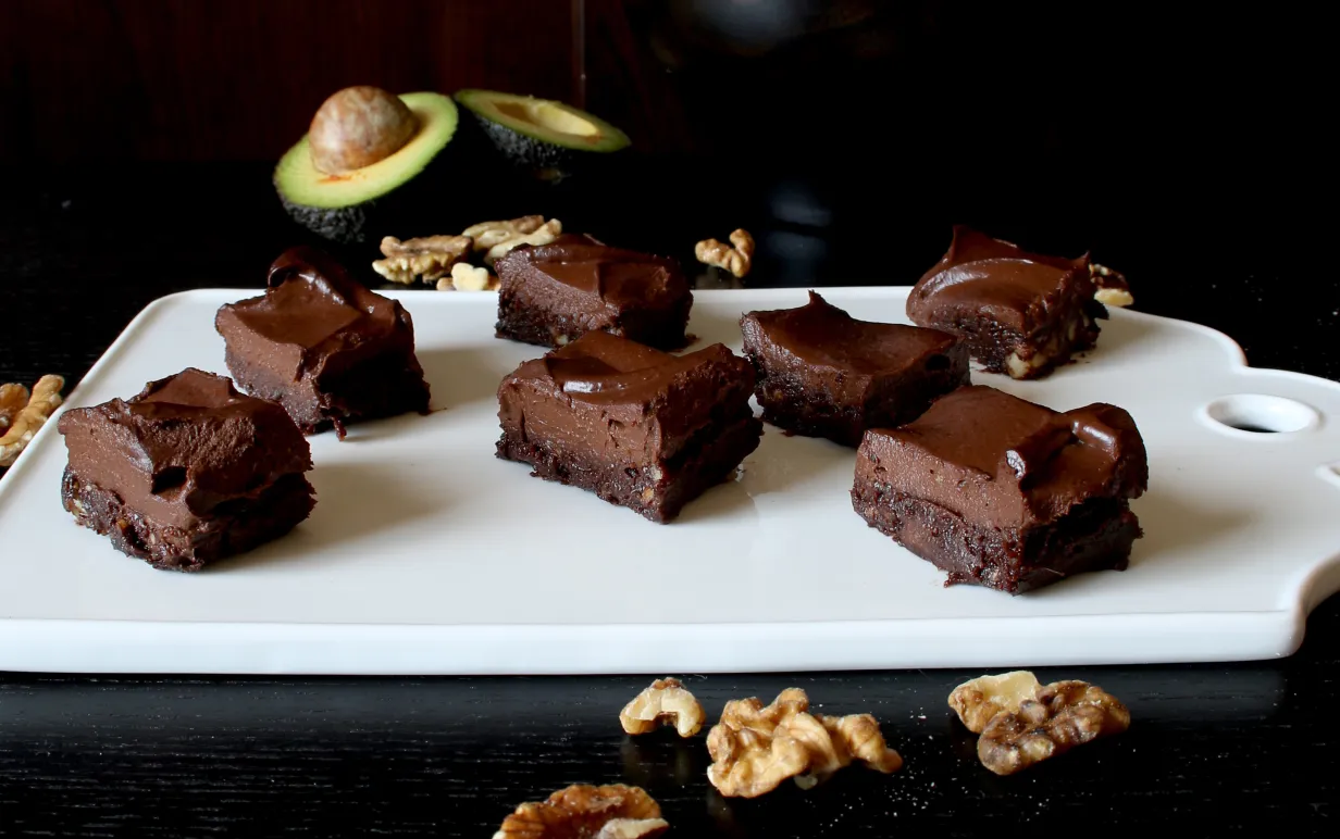 Raw brownie i bitar på en vit skärbräda.