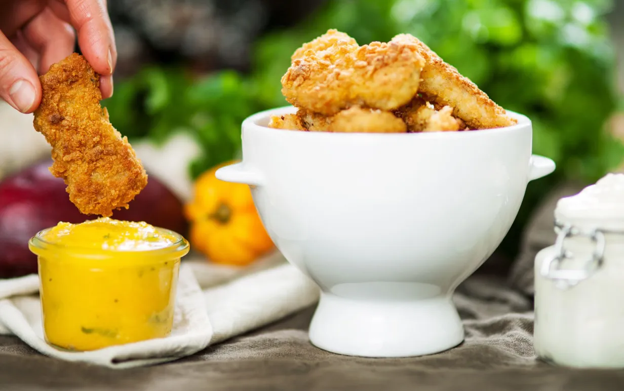 Nuggets i en vit skål, bredvid står en skål med mangosås.
