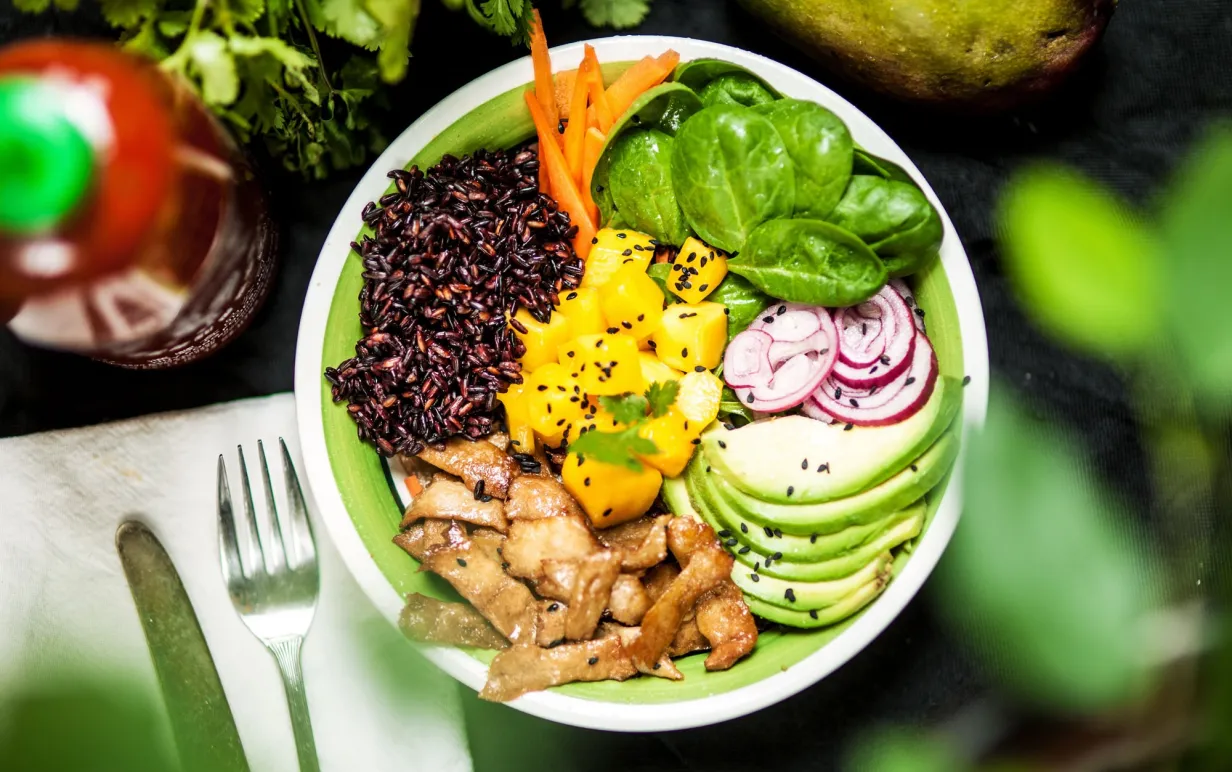 En pokébowl med babyspenat, mangobitar, vegobitar, svart ris och avokado.