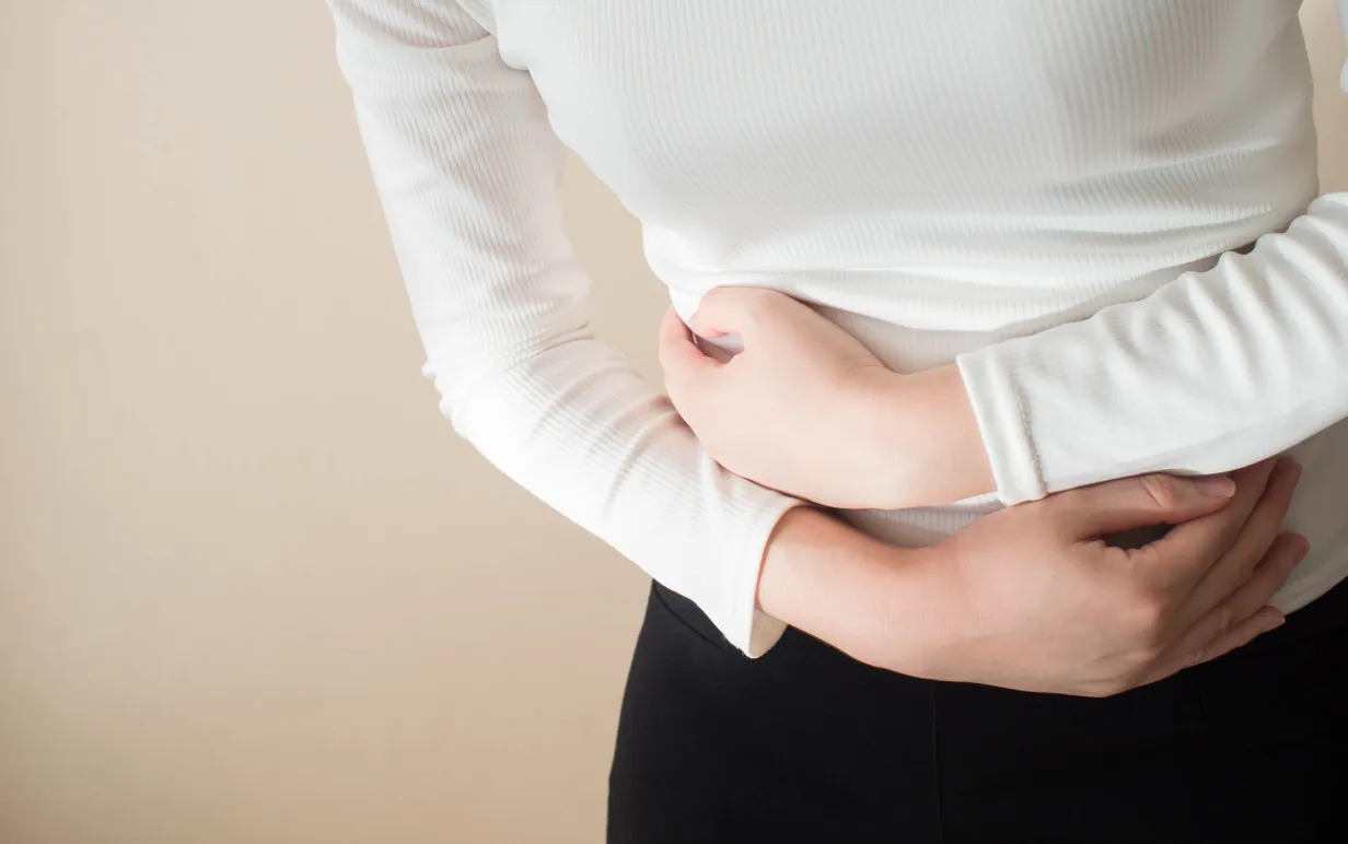 Young female suffering form stomach ache on gray background