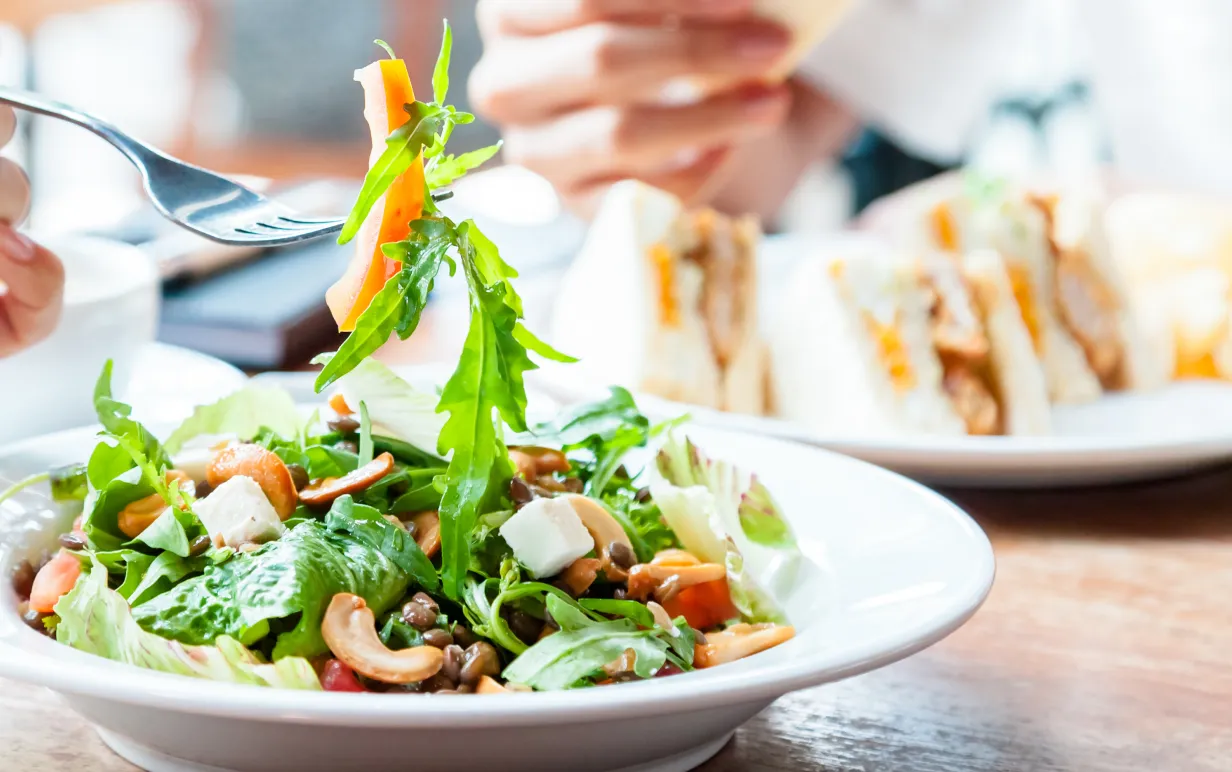 Bild på tallrik med sallad och en person som håller i en gaffel