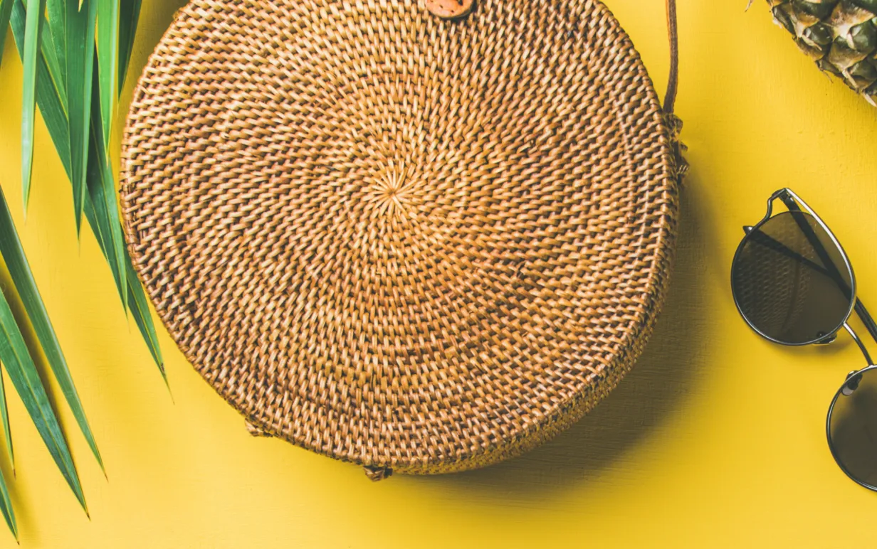 gul bakgrund med en annans, glassögon, väska och palmblad