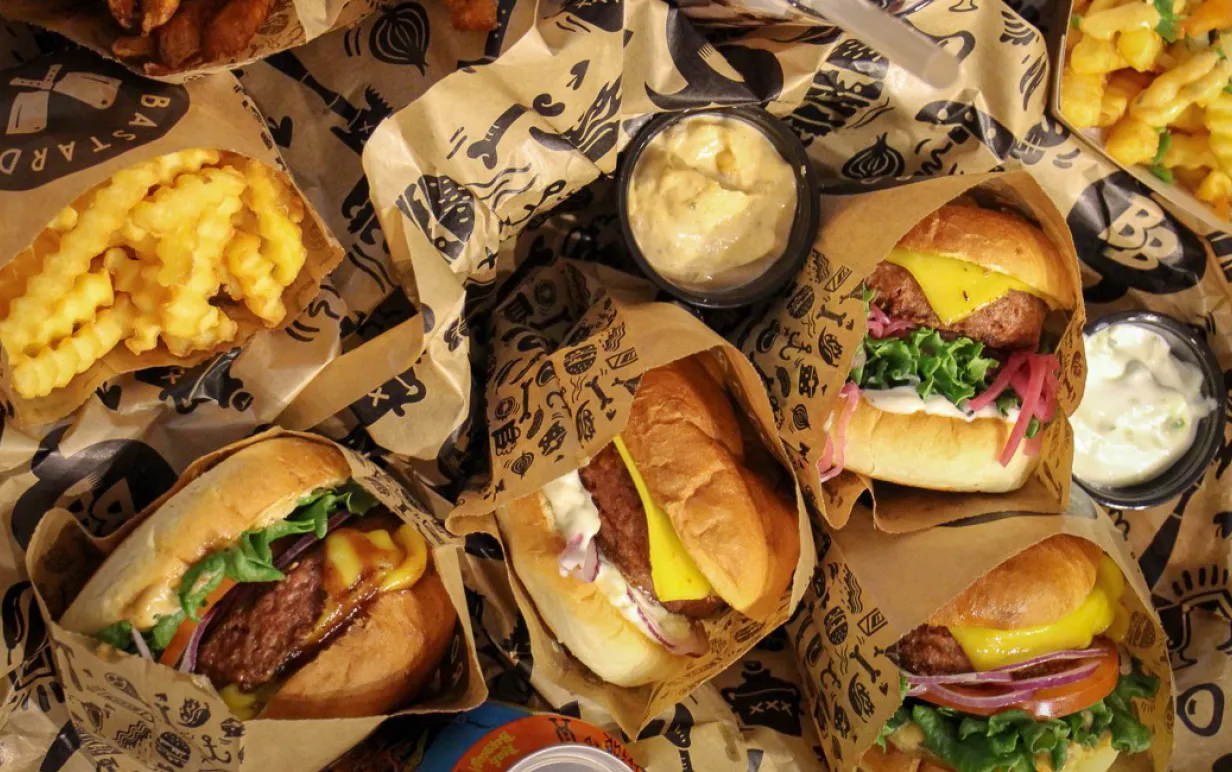 Flera veganska burgare, dressing och pommes på ett bord