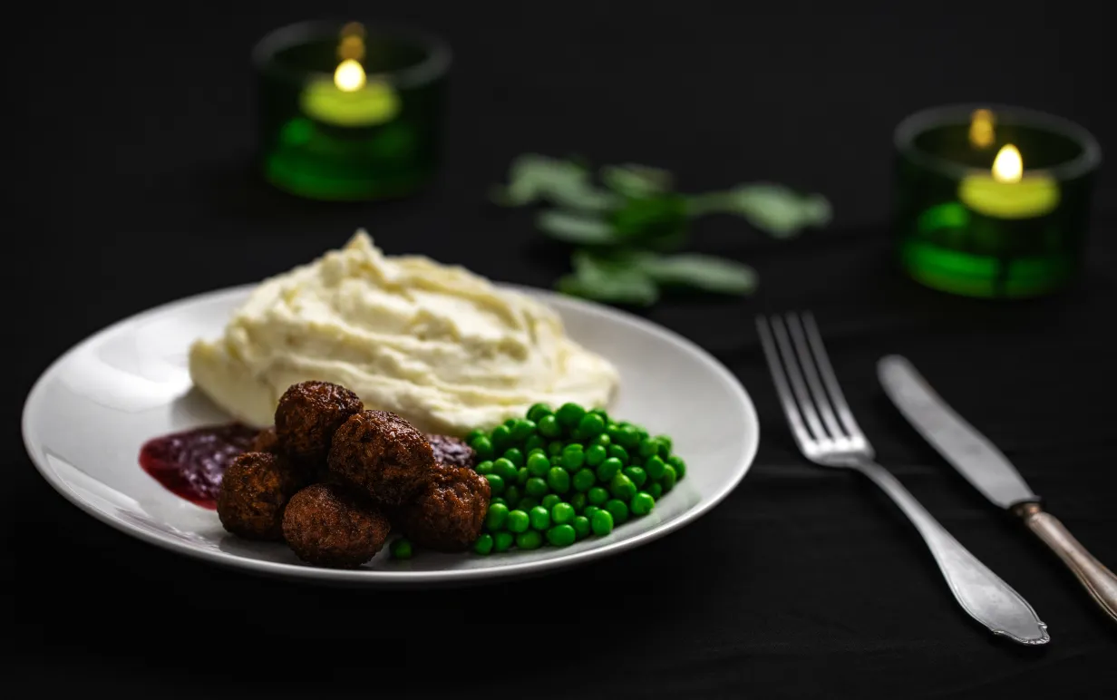 veganska köttbullar, potatismos och gröna ärtor på en vit tallrik