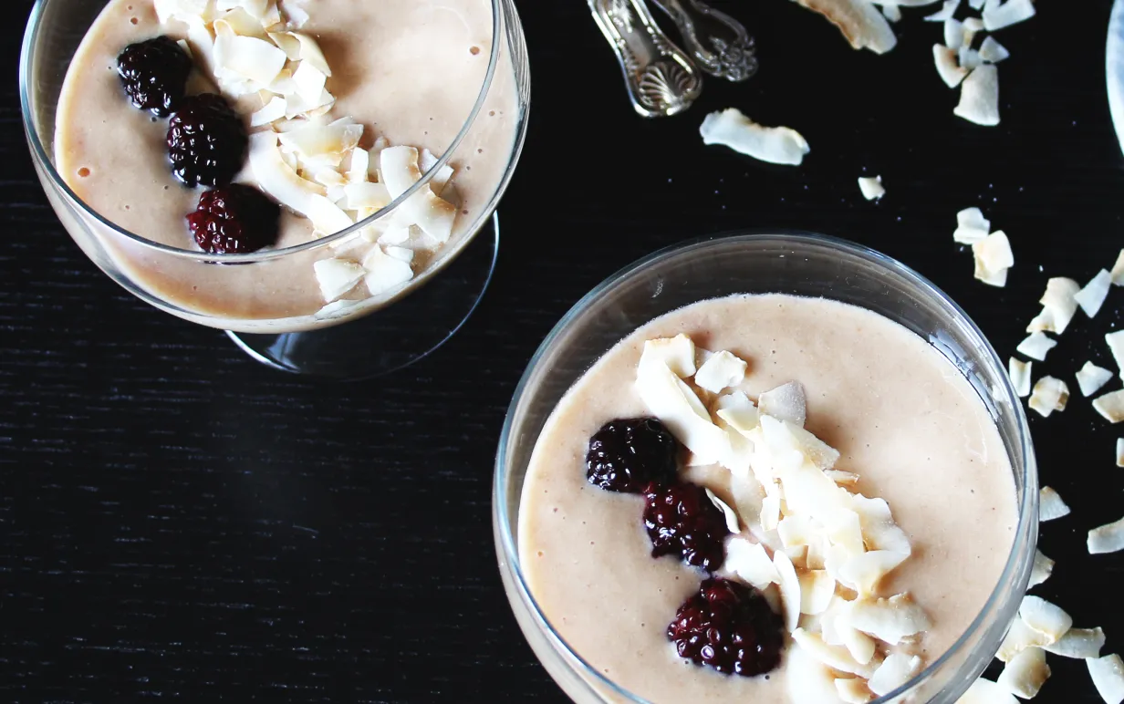 Två lucuma bowl i glasskålar, toppade med kokos och björnbär.
