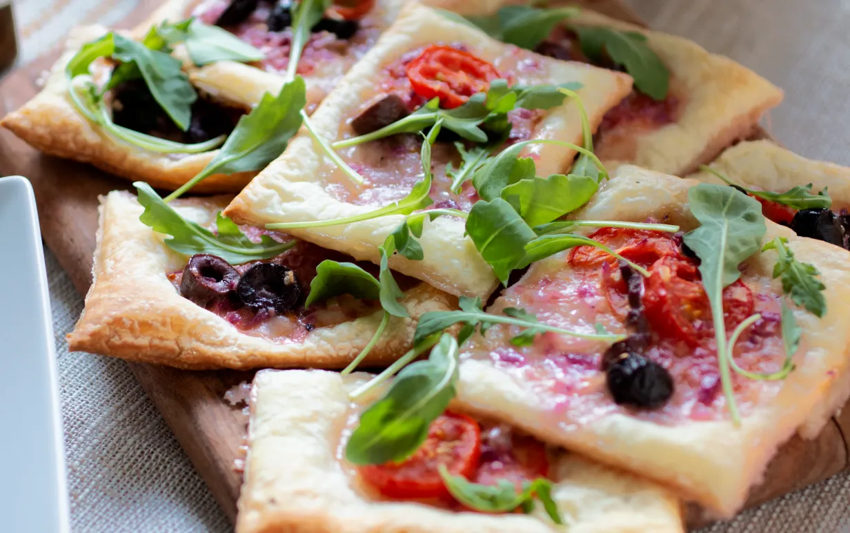 Smördegspaj med vegansk fetaost, oliver och tomat på en träbräda