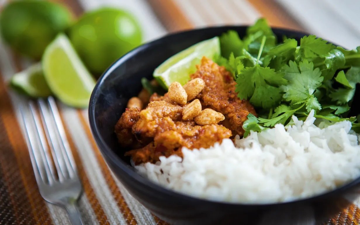 Skål med ris, vegobitar i jordnötssås och koriandersallad