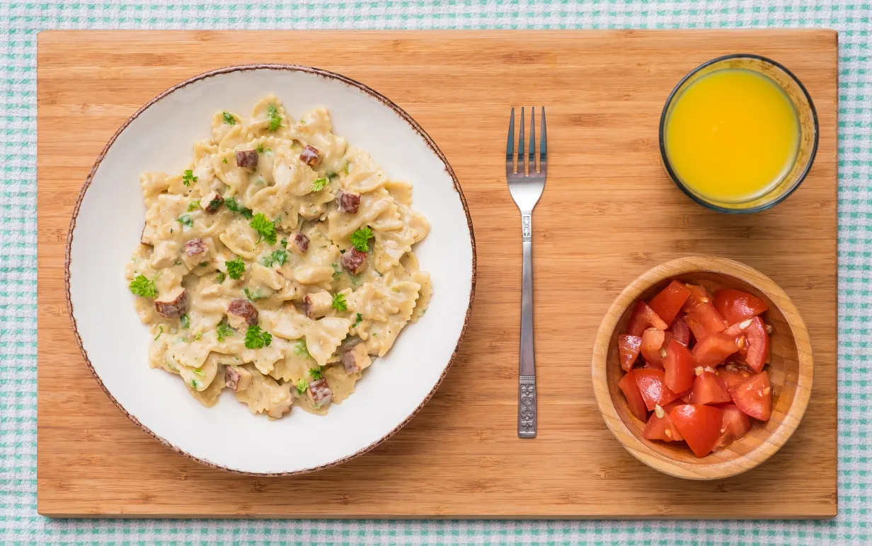 Vegansk carbonara med tofu på ett bord tillsammans med juice och tomatsallad
