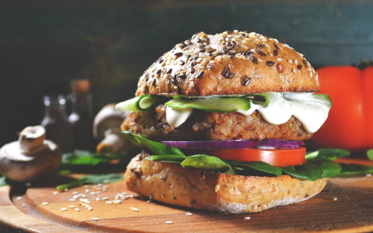 Vegansk burgare på en träbräda mot mörk bakgrund