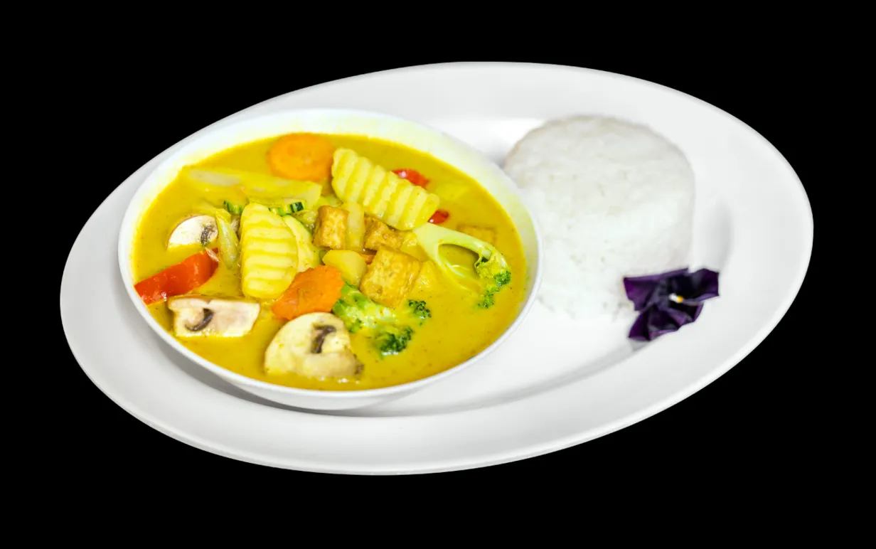 Mae Thai Stockholms veganska gula curry med tofu, grönsaker och ris på en vit tallrik med svart bakgrund.