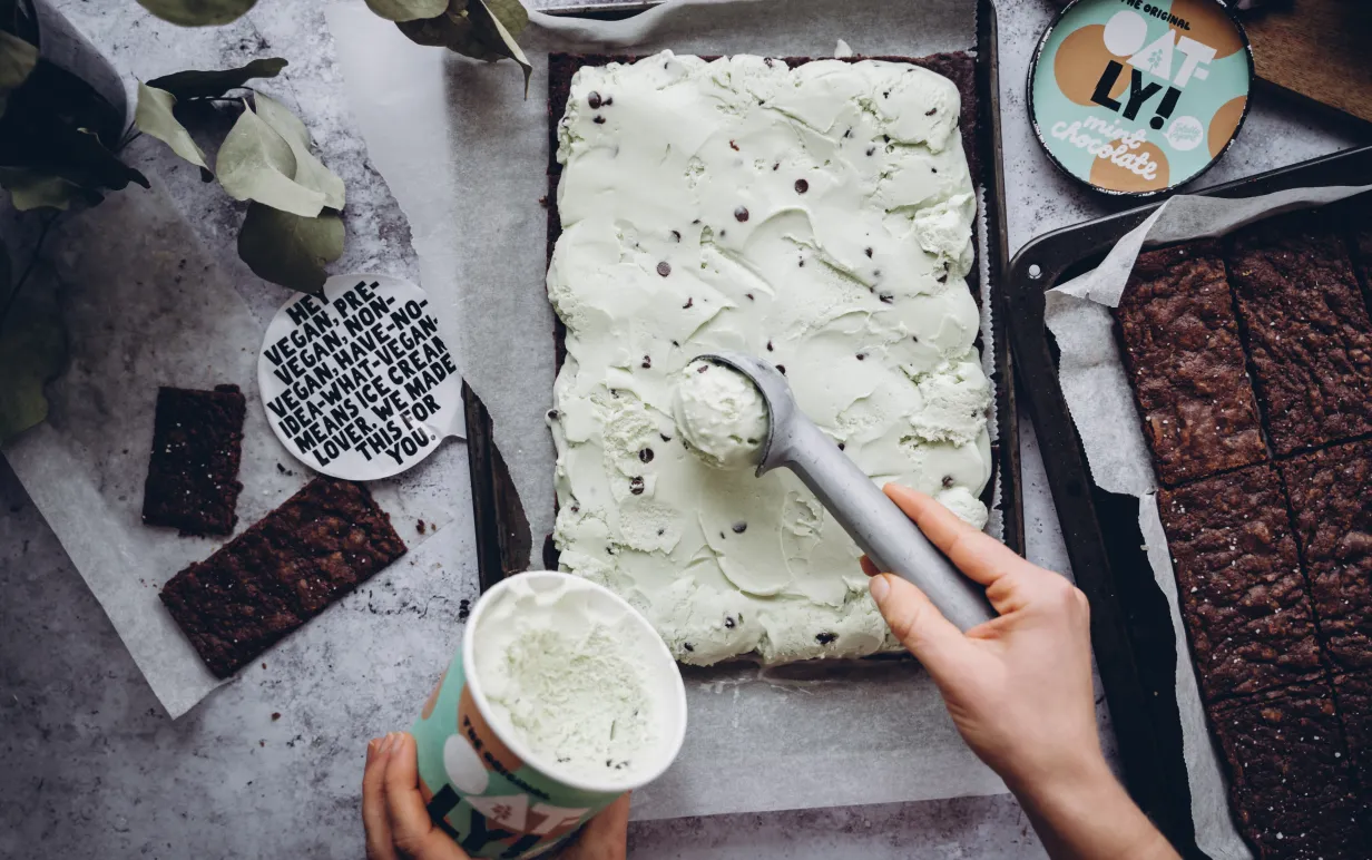 Vegansk mintchoklad glass skopas och läggs på en brownie i en långpanna.