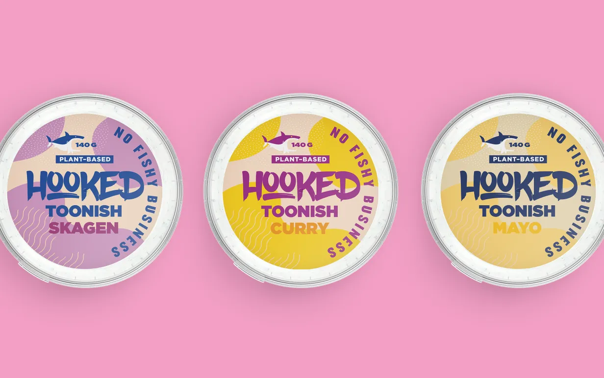 Tre röror från Hooked Foods i förpackningar mot en rosa bakgrund.