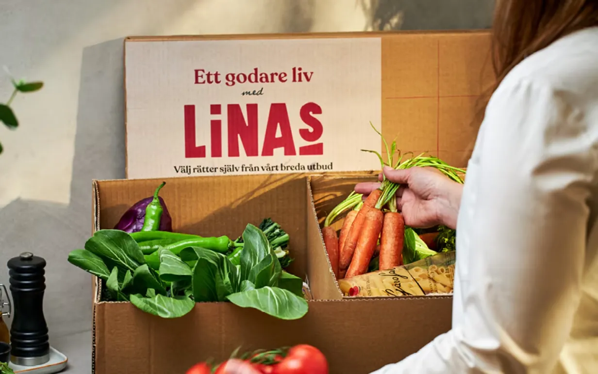 En kartong från Linas Matkasse med olika grönsaker och råvaror i.