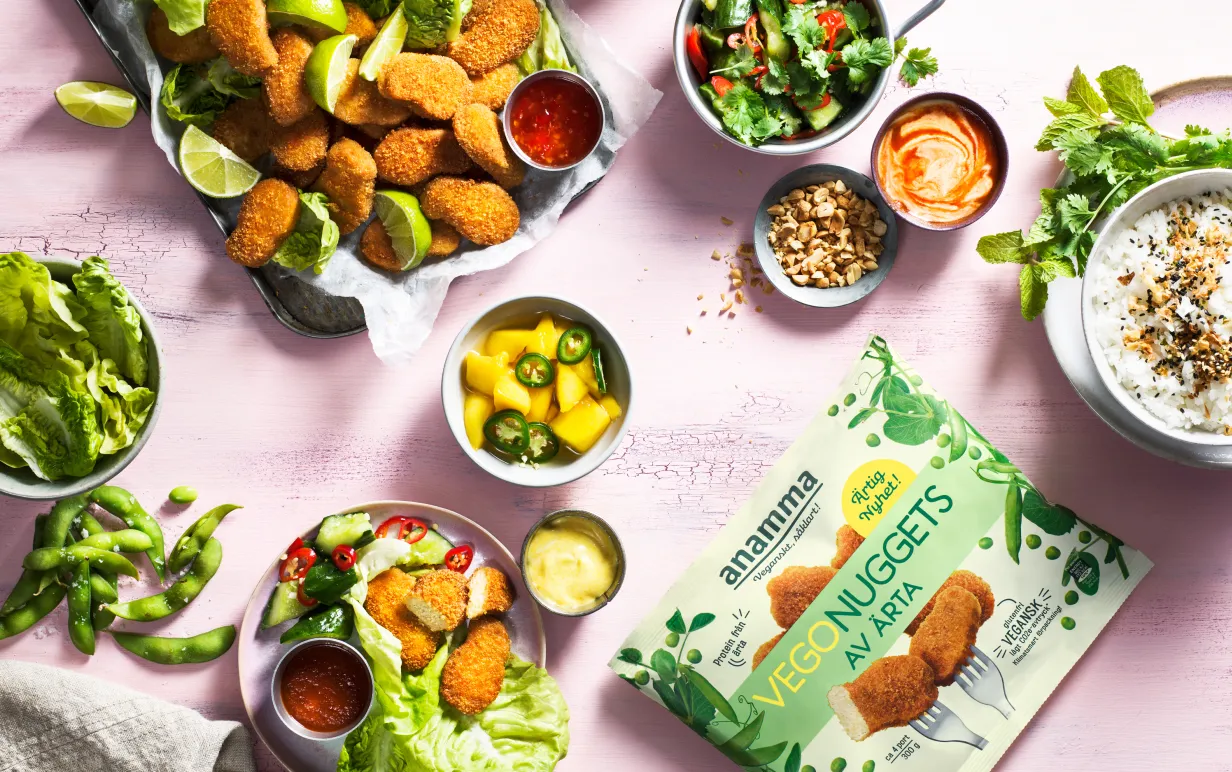 Växtbaserade nuggets i påse och uppdukade på olika sätt med mycket grönt på ett rosa bord.