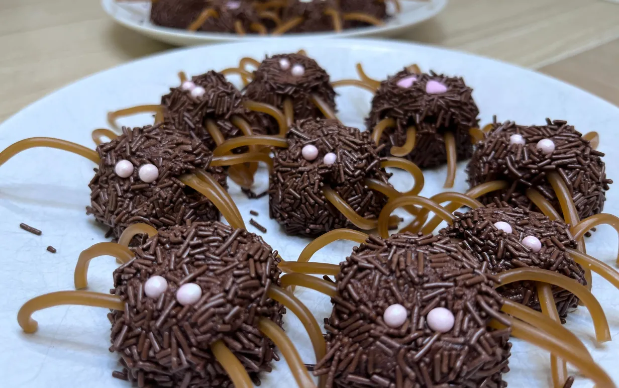 Chokladbollar som ser ut som spindlar med kolaremmar som ben och strössel som ögon