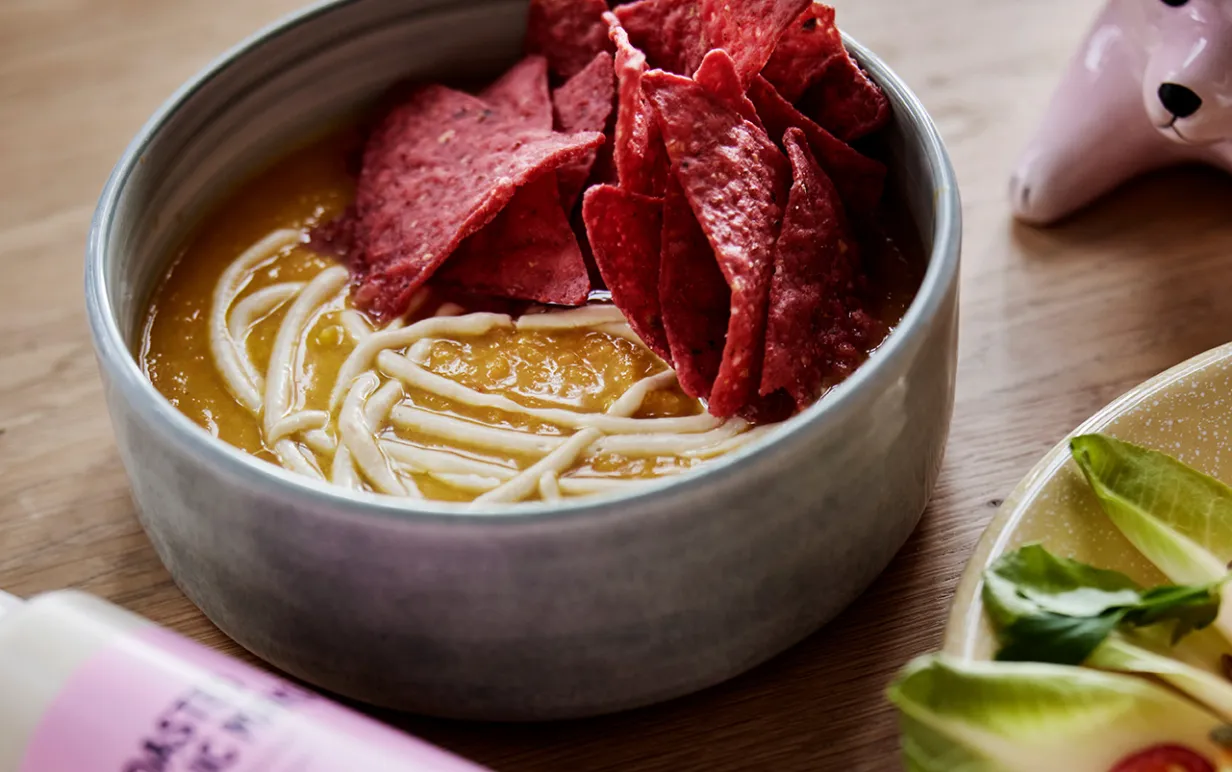 Pumpasoppa i en skål med nachos på sidan om soppan.