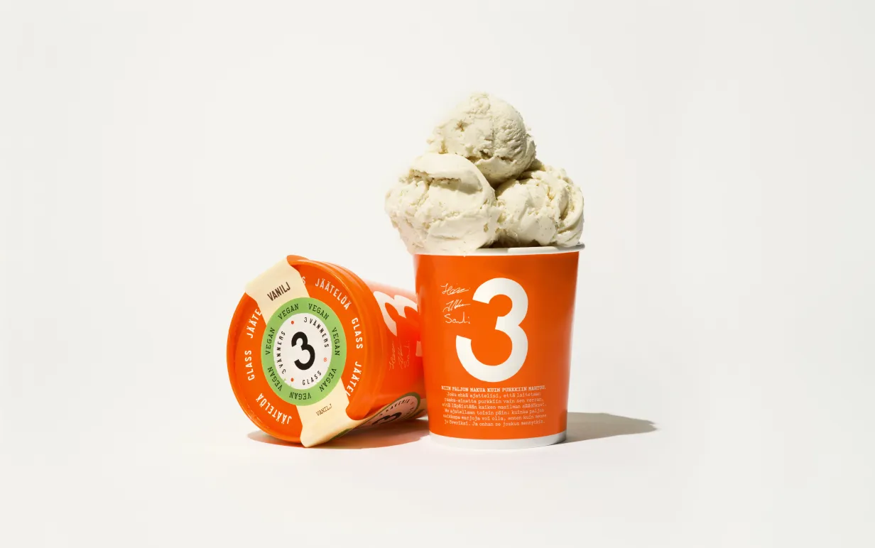 Vegansk vaniljglass i orange pappburk mot vit bakgrund