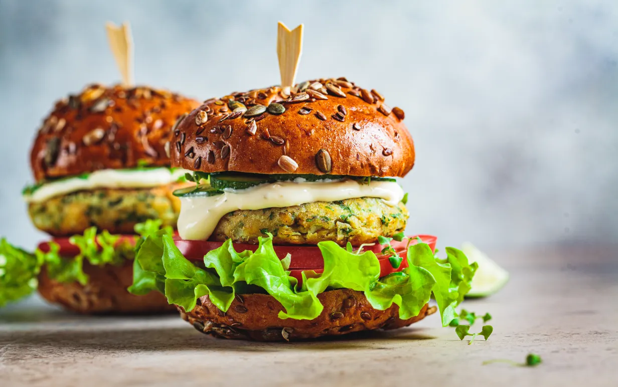 Vegan falafel burger med grönsaker och sås, mörk bakgrund. Hälsosam mat koncept.