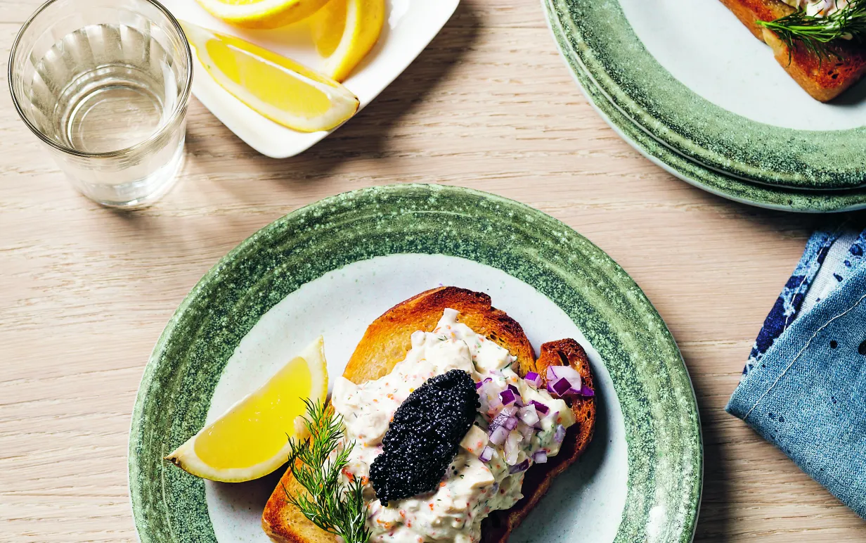 Skagenröra på toast på två tallrikar på ett ljust träbord