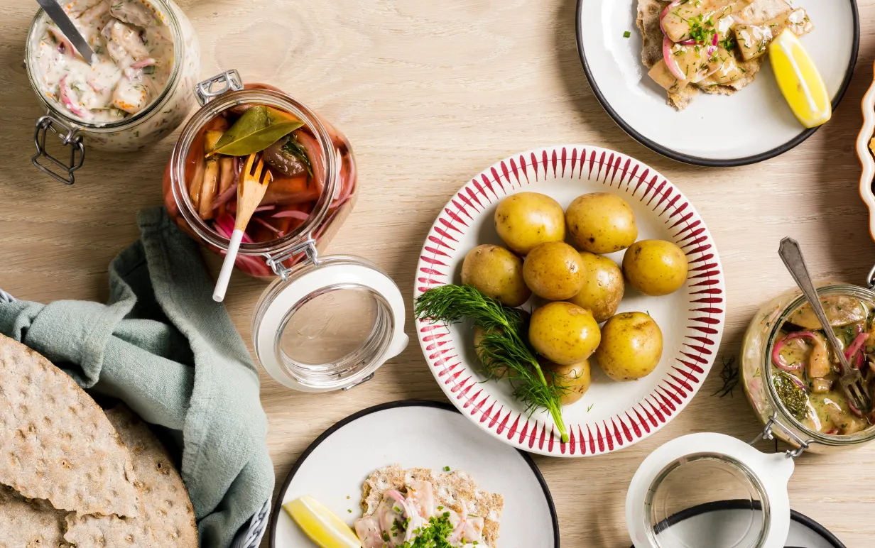 Flera olika veganska sillar uppdukade på ett bord med kokt potatis och knäckebröd.