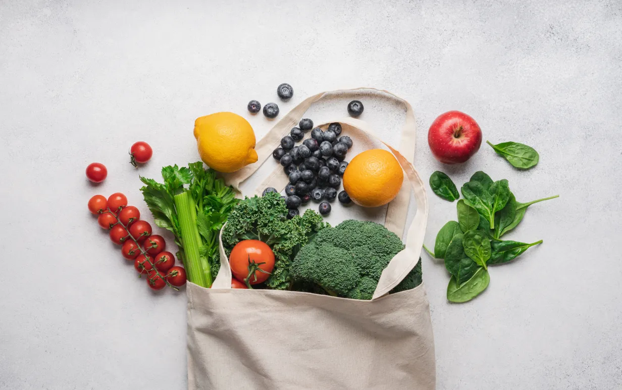 Handla hälsosam mat i bomullspåse med noll avfall. Selleri, grönkål, tomat, spenat, blåbär, broccoli, citron, apelsin ovanifrån