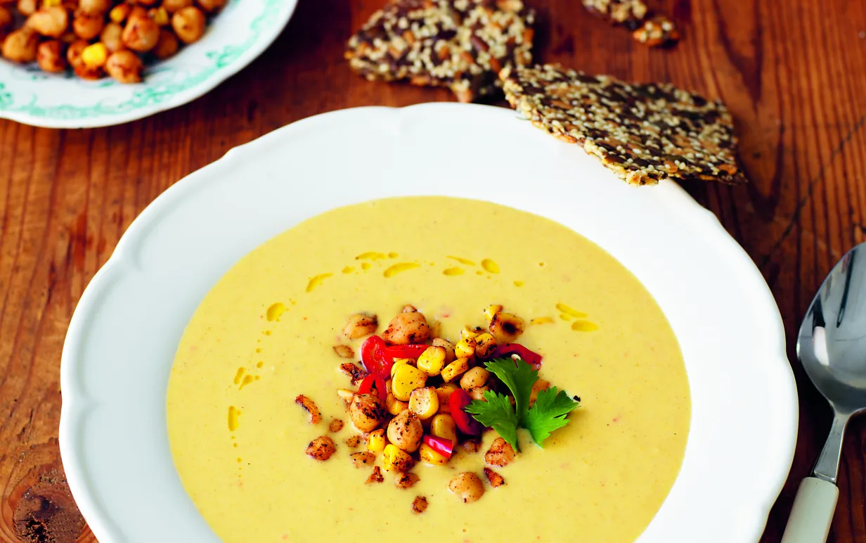 Majssoppa på ett träbord med en sked på sidan