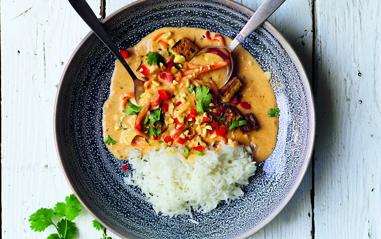 Jordnötsgryta med tofu i en djuptallrik på ett vitt bord