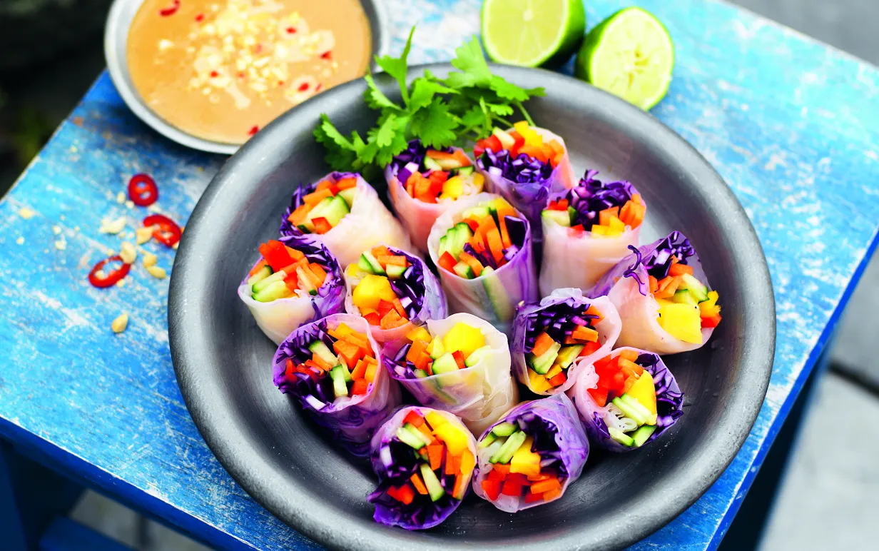 Vietnamesiska vårrullar i ett fat på ett turkost bord ute i naturen