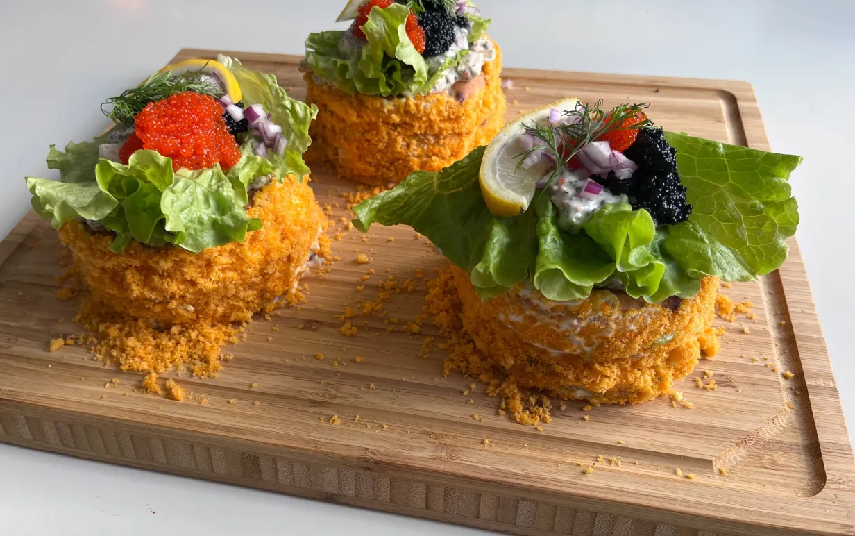 Tre runda minismörgåstårtor på en skärbräda i trä