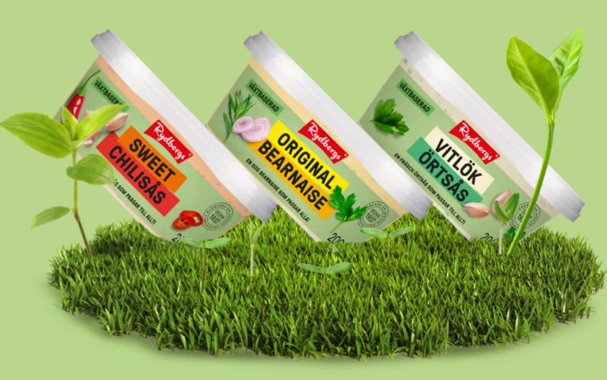 tre plastburkar med sås snedställda mot en grön bakgrund med gräs