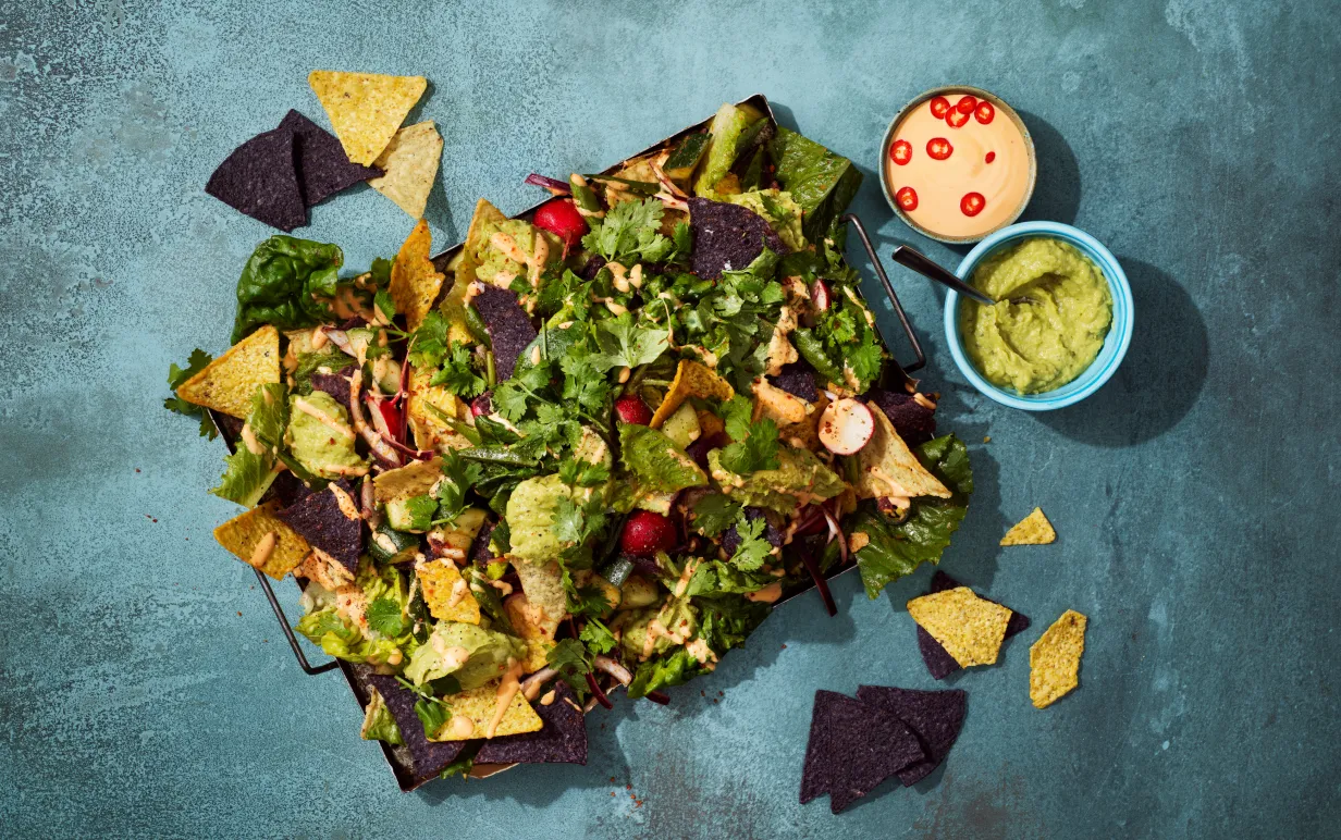 en bricka med nachos och topping på ett mörgrått bord