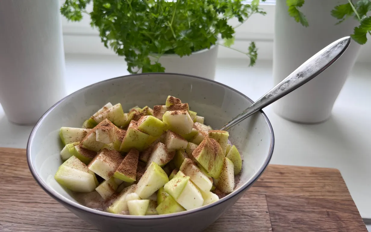 gröt med äpple i en skål på ett träbord