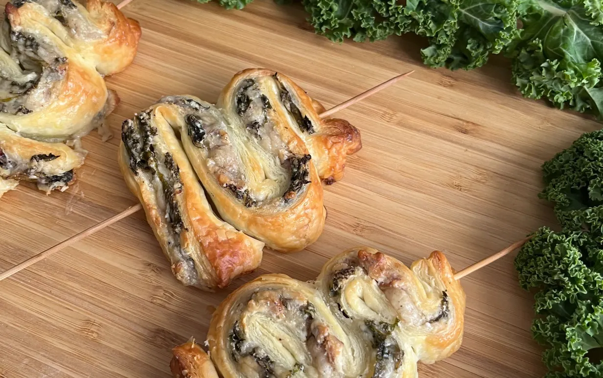 Tre grönkålsgranar på en skärbräda i trä med grönkål runt