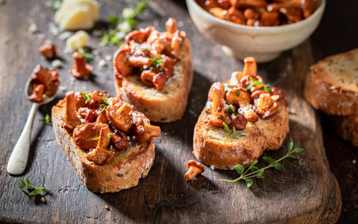 Tre kantarellmackor på en skärbräda i trä