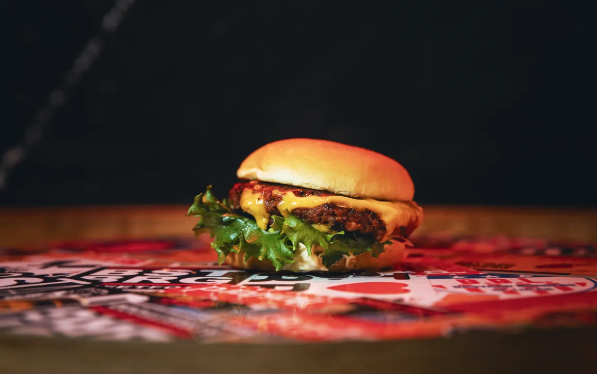 En vegansk hamburgare på ett färgglatt bord och en mörk bakgrund