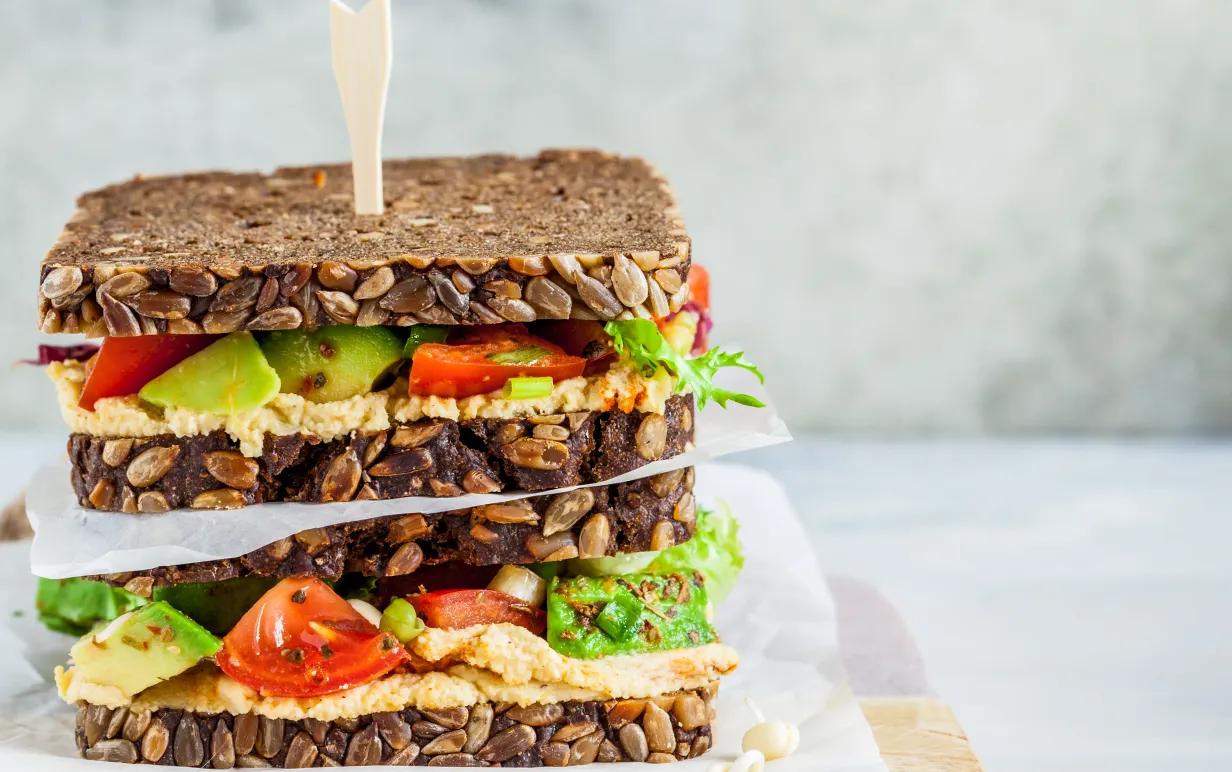 Veganska mackor med hummus, tomat, avokado och sallad på fullkornsbröd.