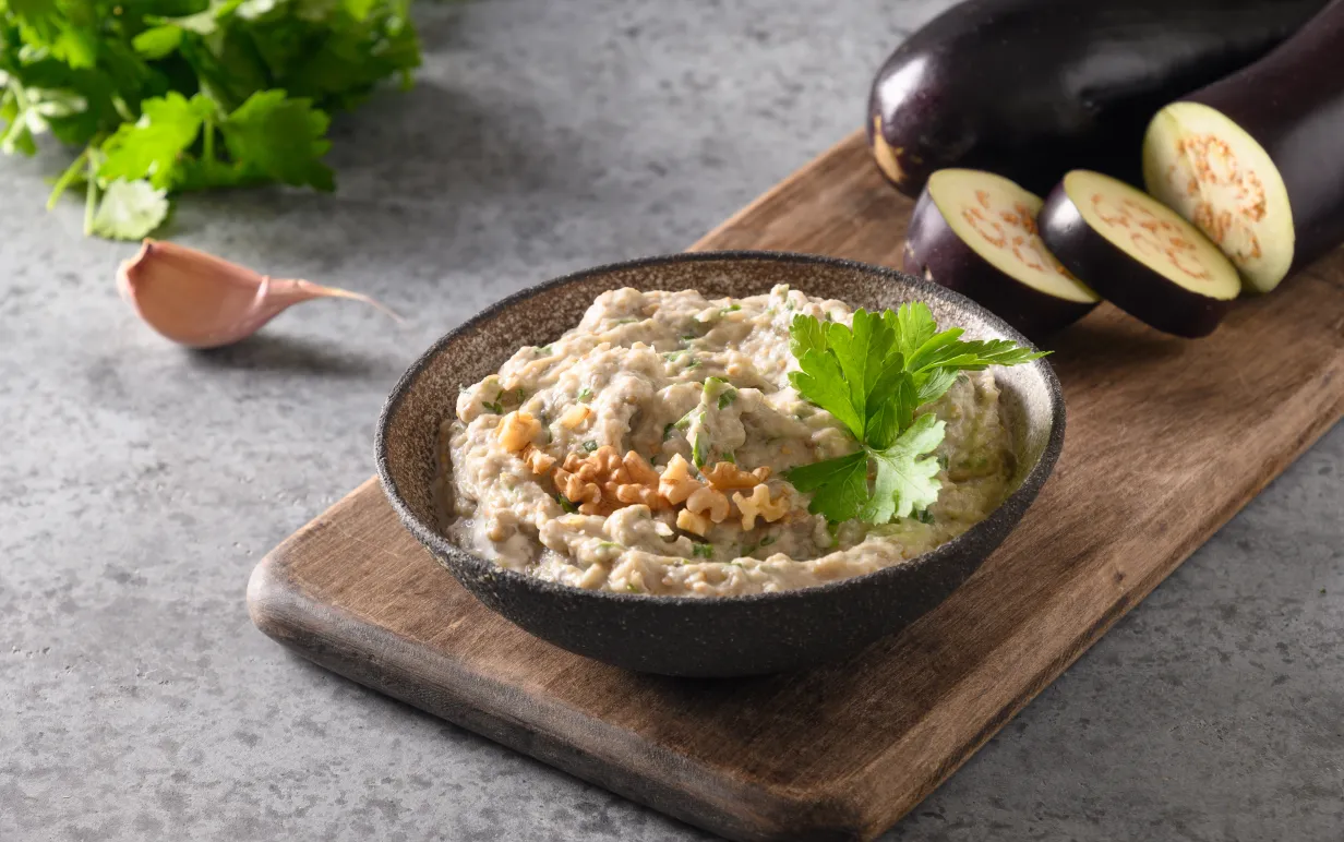 Baba ganoush i en tallrik på en skärbräda.