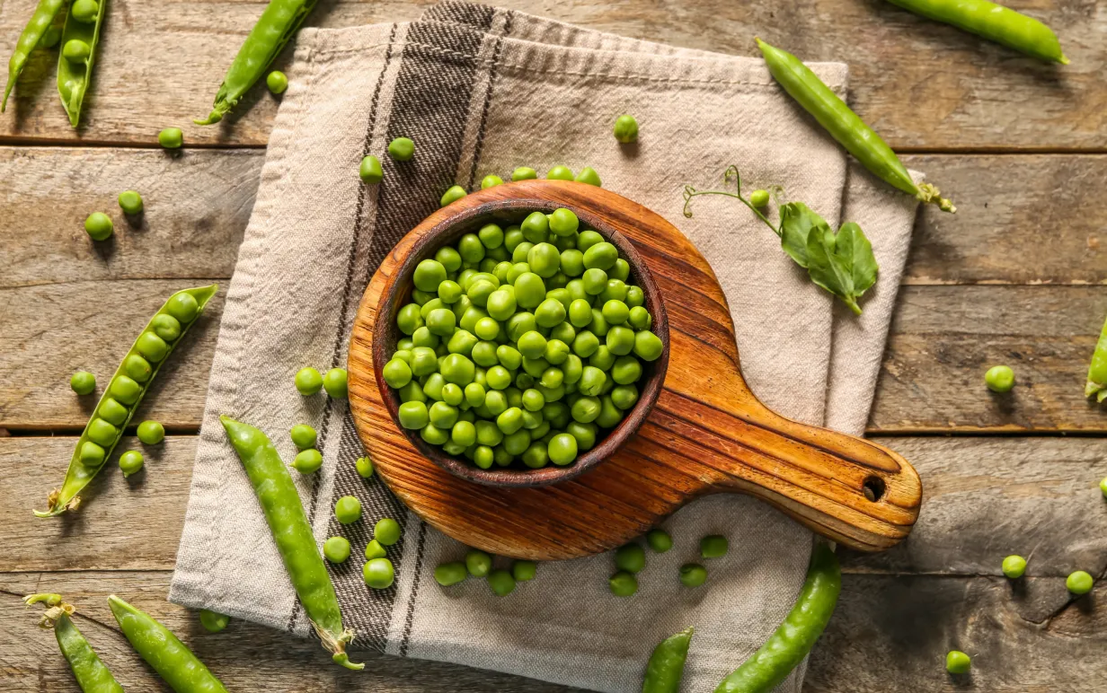 En skål med gröna ärtor mot en träbakgrund