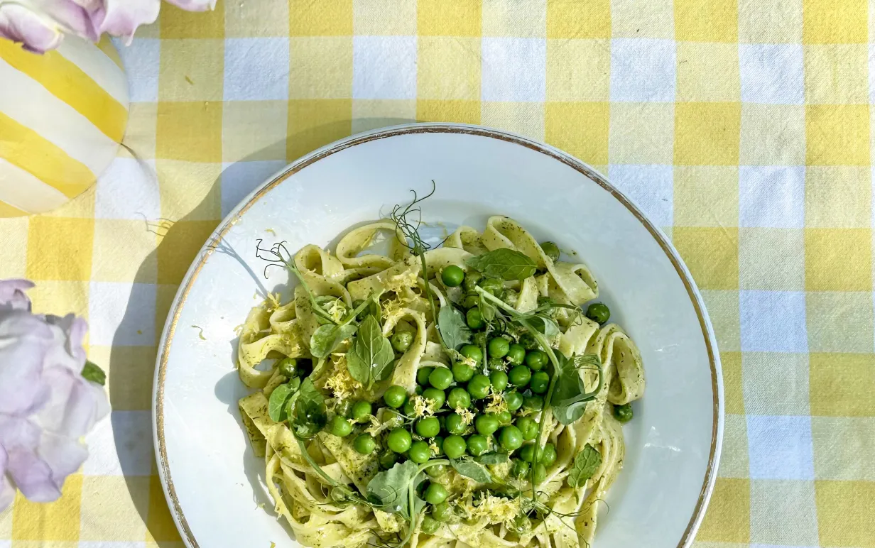 Tallrik med pasta och ärtor på en gulrutig duk