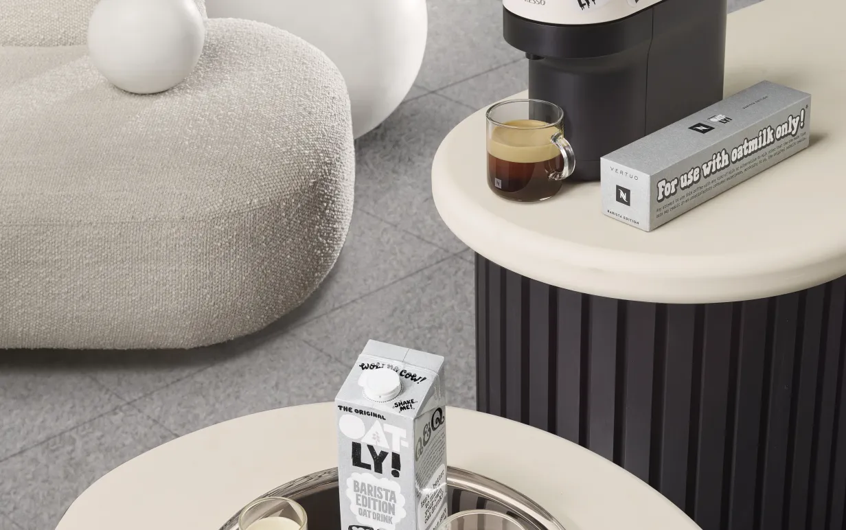 Nespressomaskin på ett bord och oatlyprodukter på ett annat bort