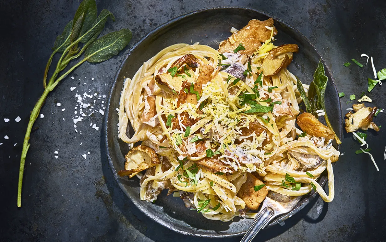 Vegansk kycklingpasta i en svart djuptallrik på ett svart bord