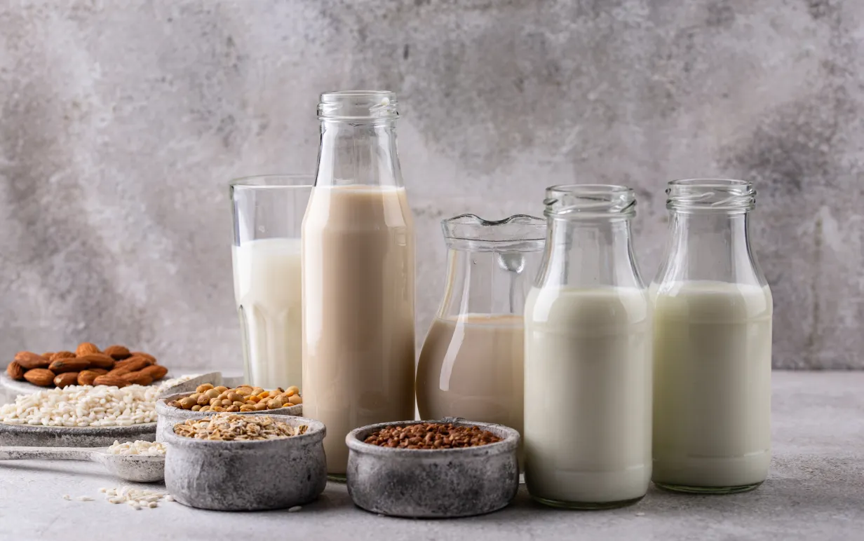 Fyra glasflaskor och ett glas med växtbaserad dryck