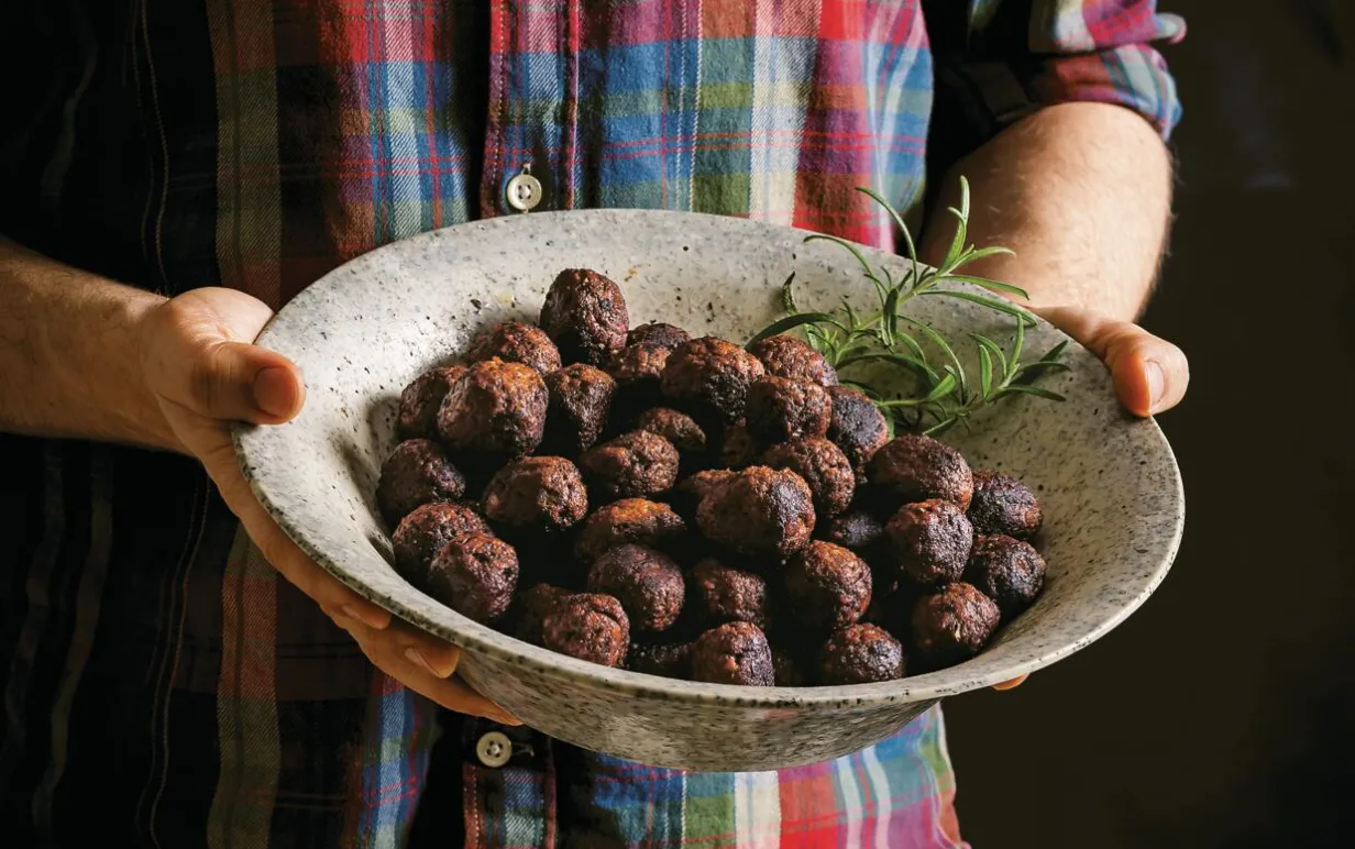 En man som håller i en skål med veganska julköttbullar