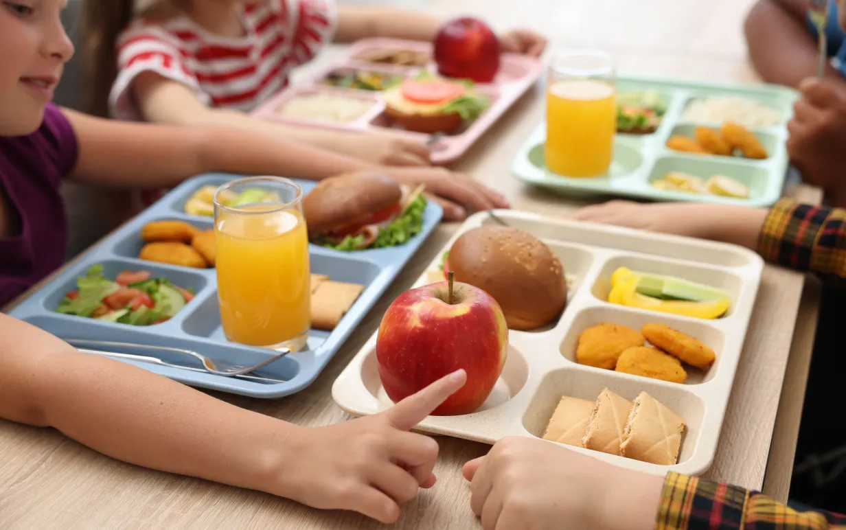 Små barn äter lunch på träbord i skolmatsalen, närbild