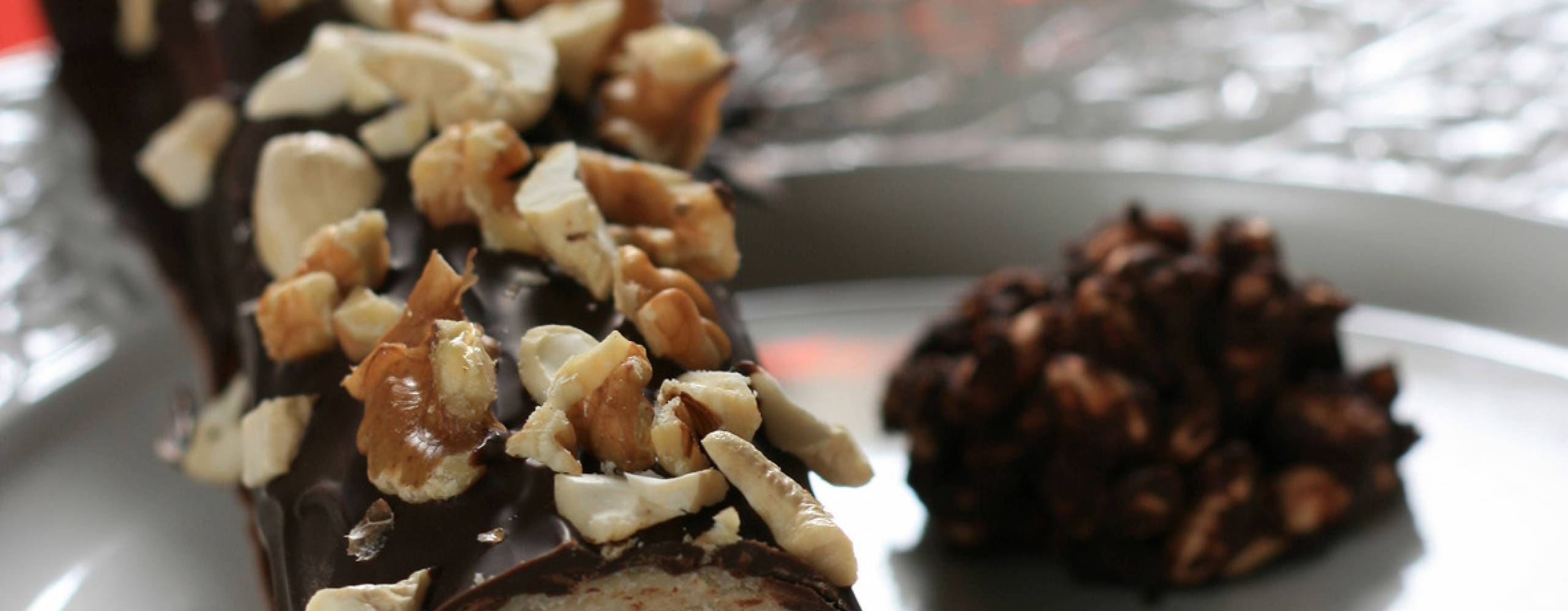 Marsipan- och nougatrulle, dekorerad med cashewnötter och valnötter, på ett fat.