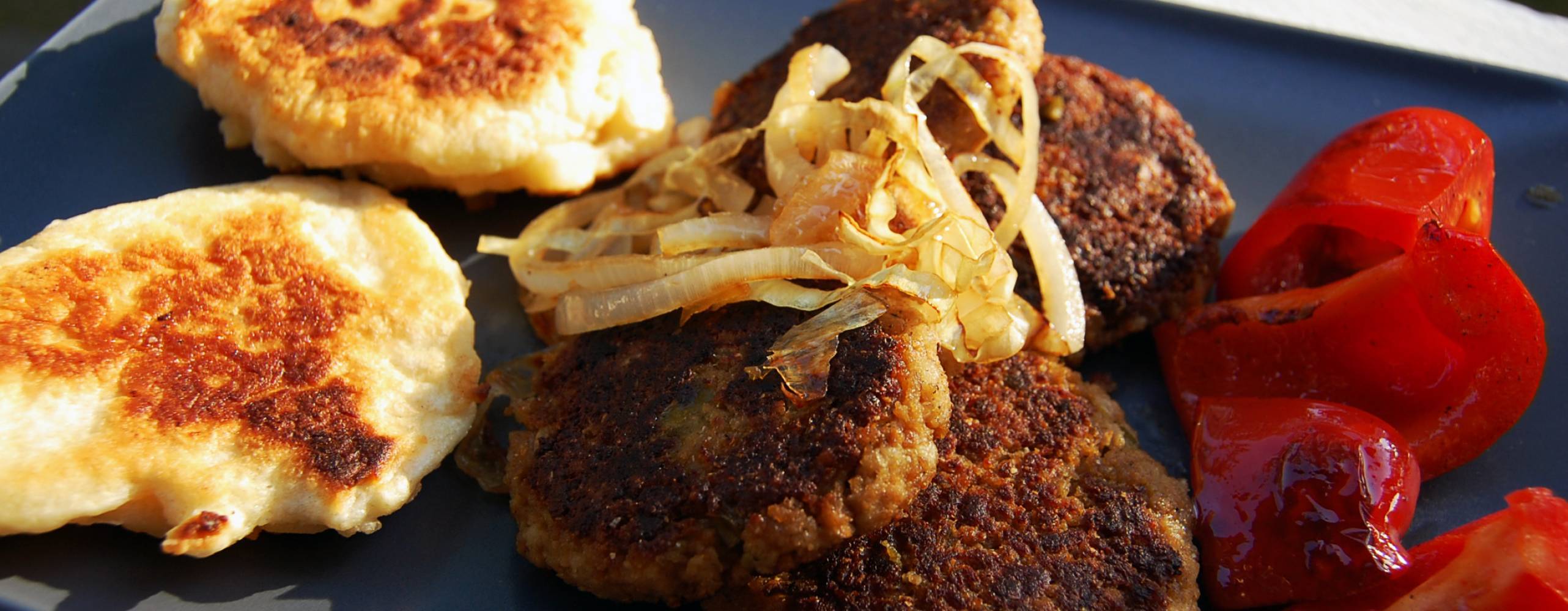 Pljeskavica ligger på ett grått fat