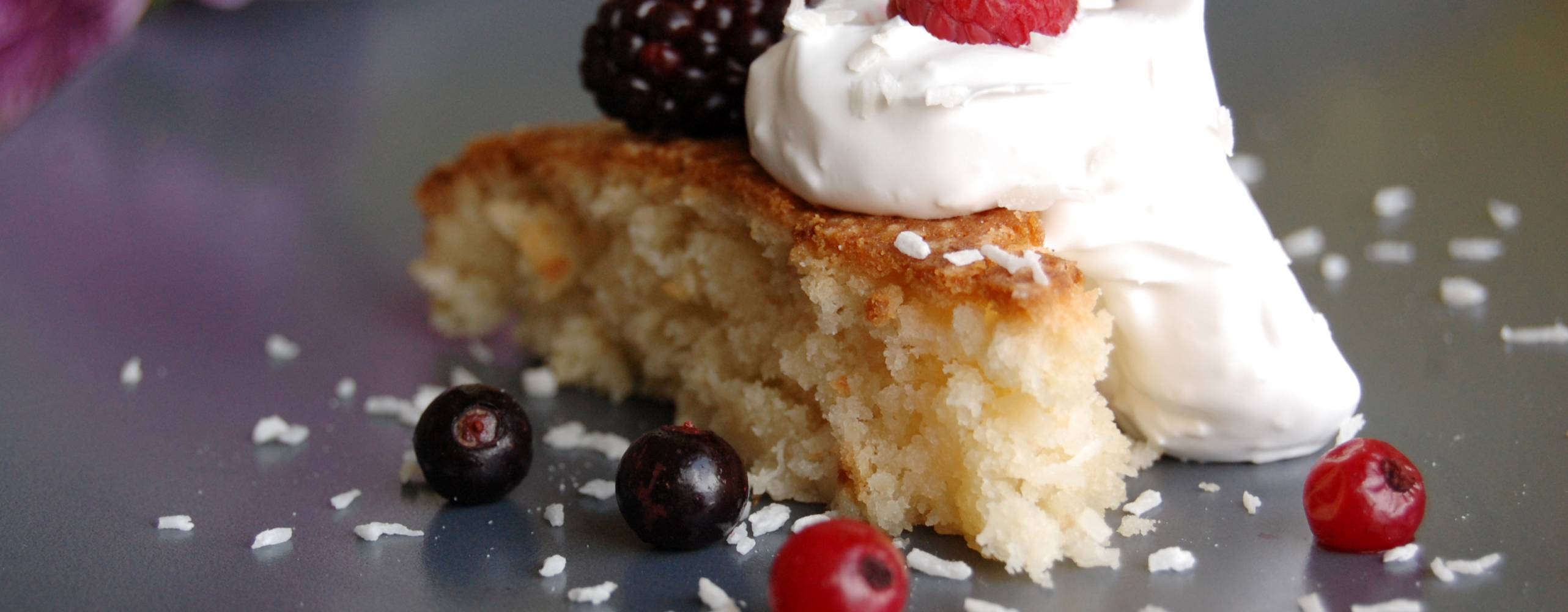 Kokoskaka med grädde, dekorerad med björnbär, hallon, svarta och röda vinbär.