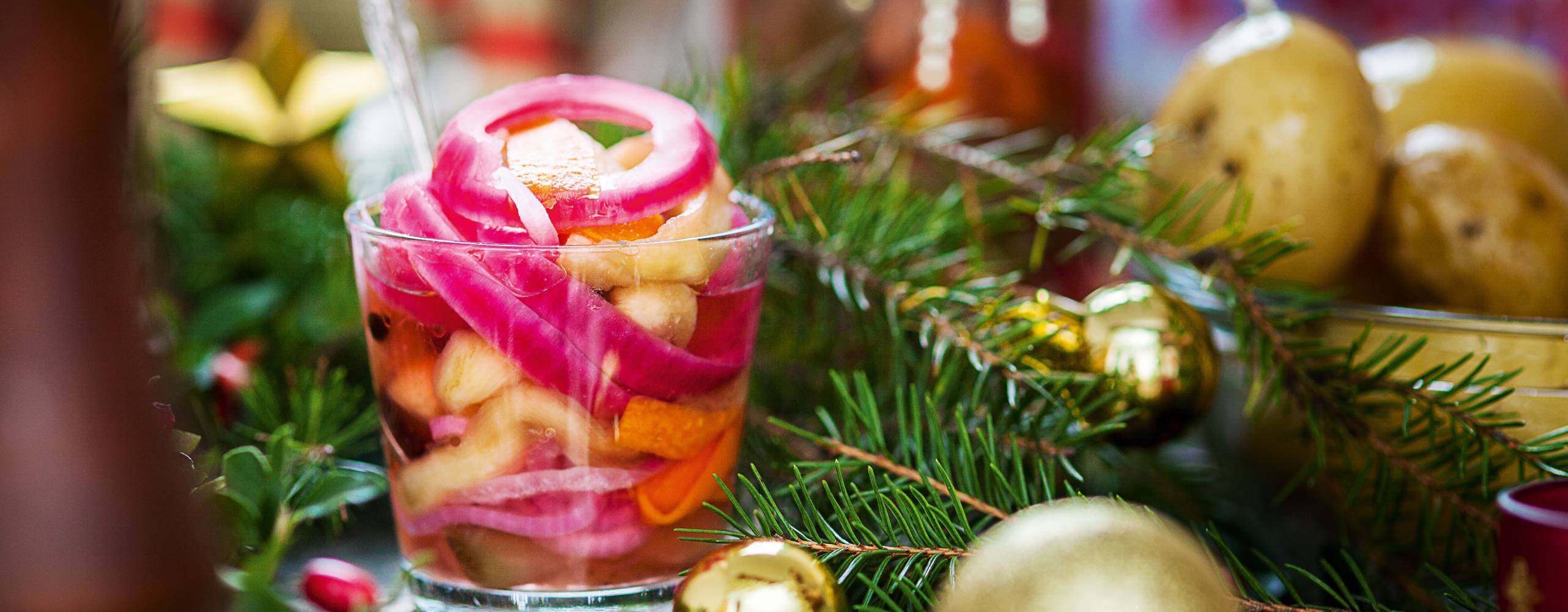 Bild på vegosill i genomskinlig behållare intill en guldfärgad julkula